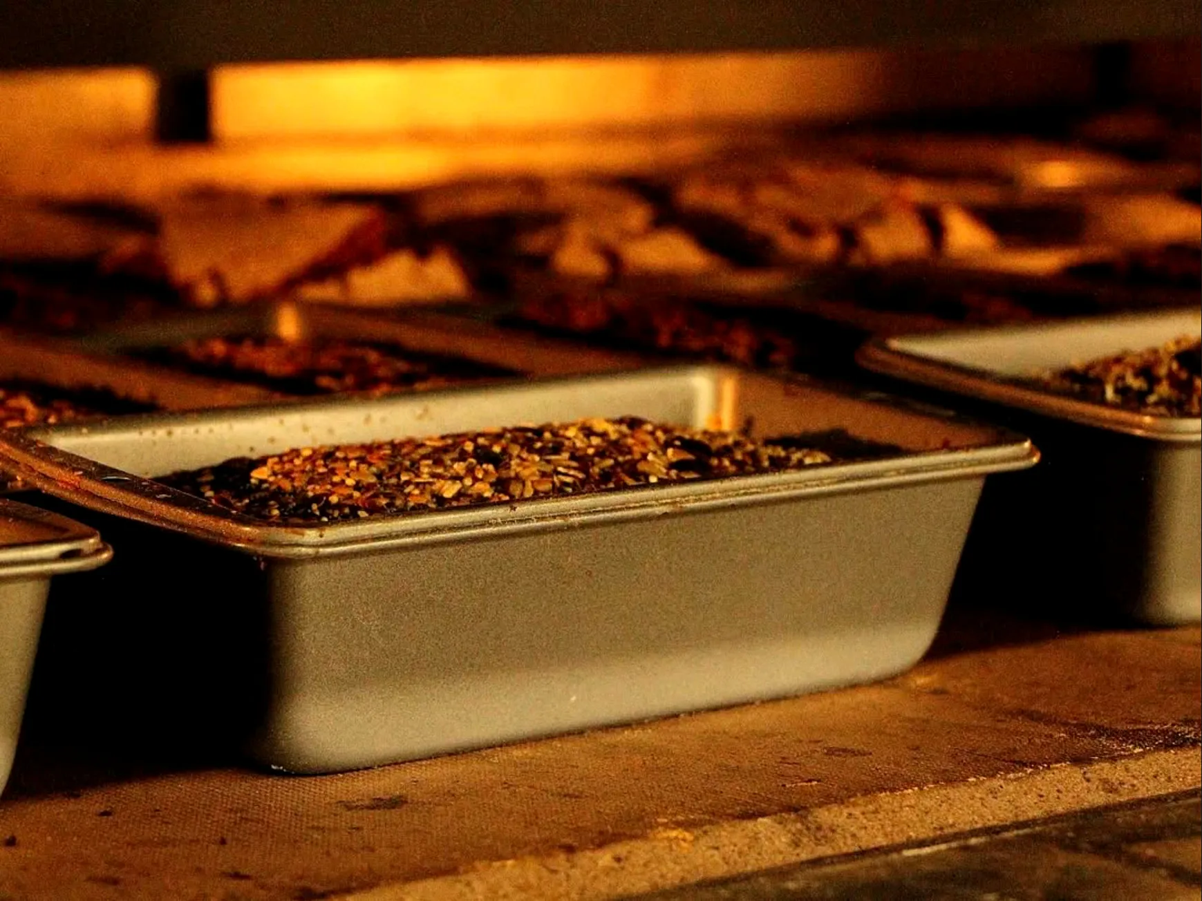 Formas de pão no forno, iluminadas pela chama.